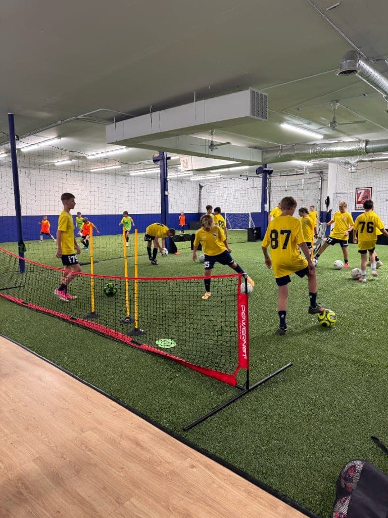 Youth players in yellow kits training on indoor turf at STAR Soccer Lab
